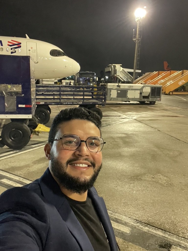 Gabriel de Freitas Carvalho wearing glasses and a blazer at an airport apron at night
