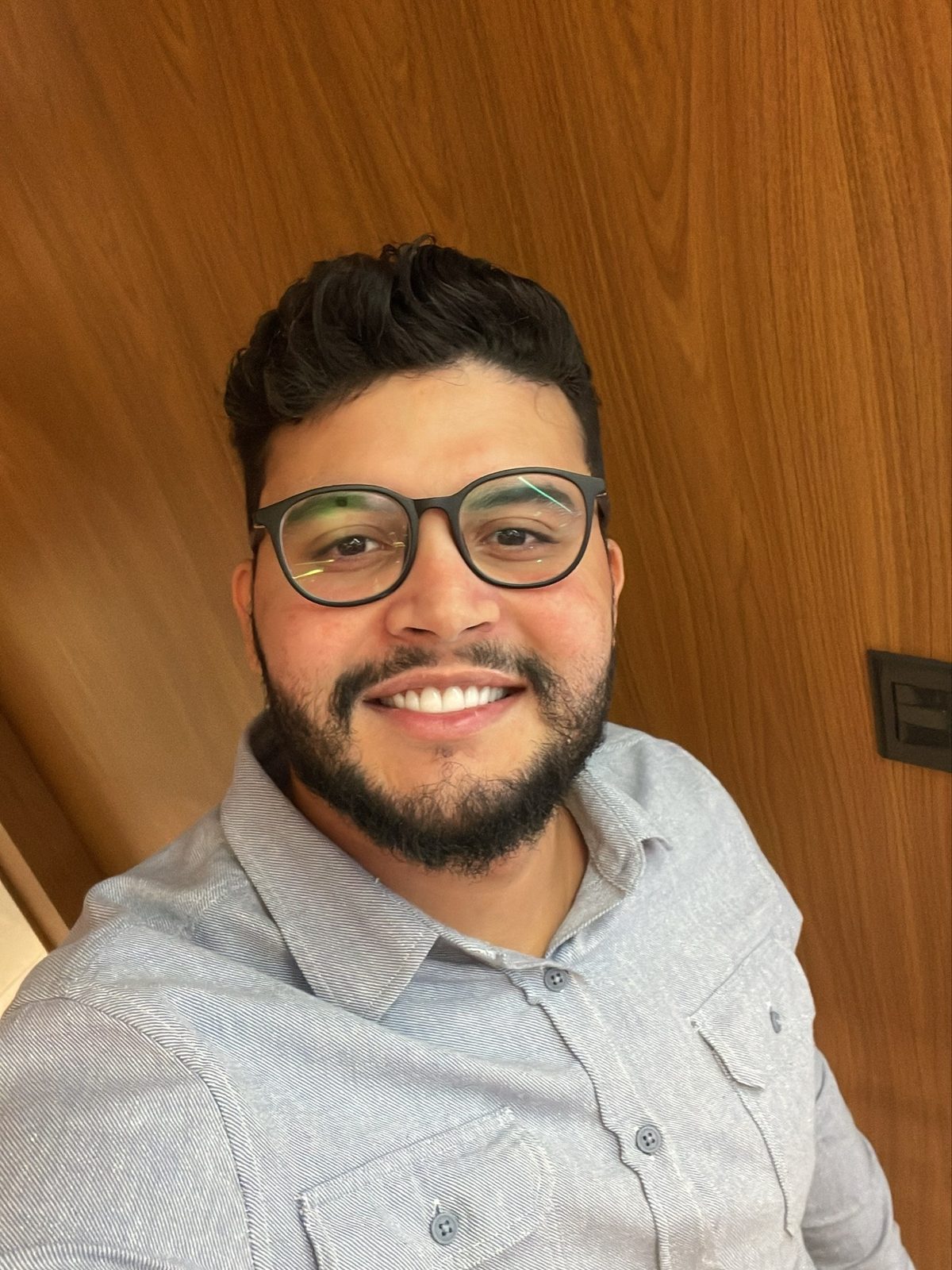 Portrait of Gabriel de Freitas Carvalho smiling, wearing glasses and a light blue shirt